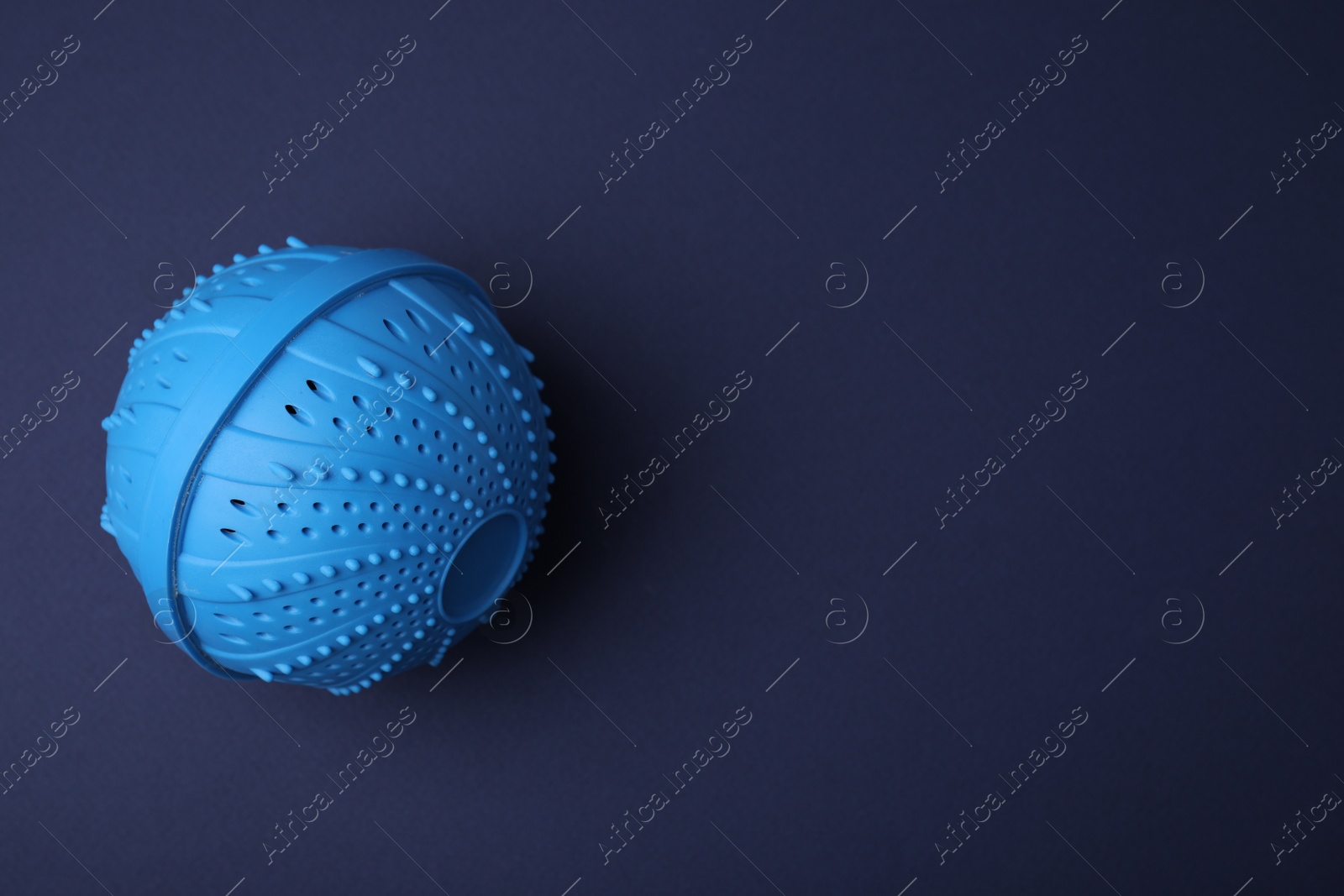 Photo of Laundry dryer ball on dark blue background, top view. Space for text