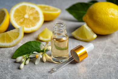 Photo of Citrus essential oil, flower and lemons on light table