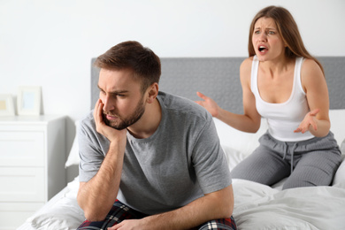 Photo of Young couple quarreling in bedroom. Relationship problems