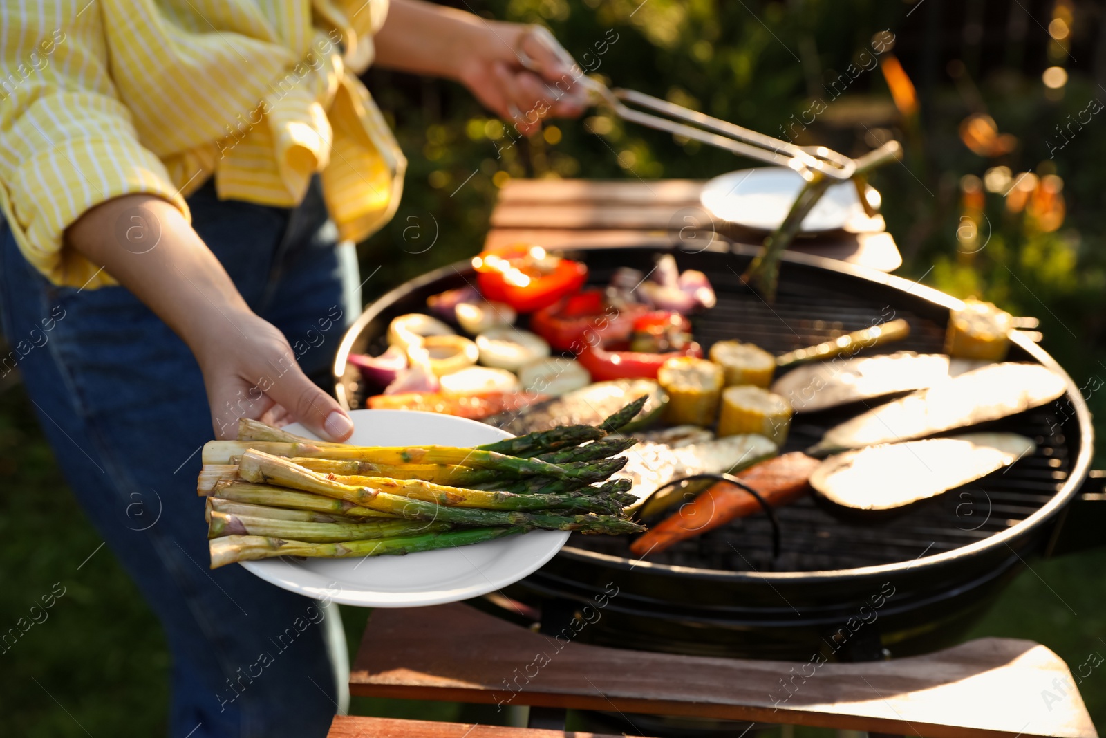 Photo of Woman cooking vegetables on barbecue grill outdoors, closeup