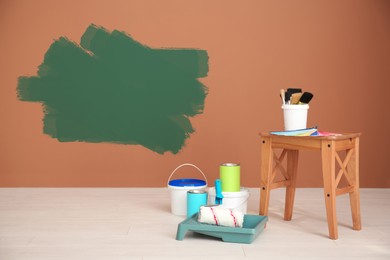 Set with decorator's tools and paint on floor near color wall