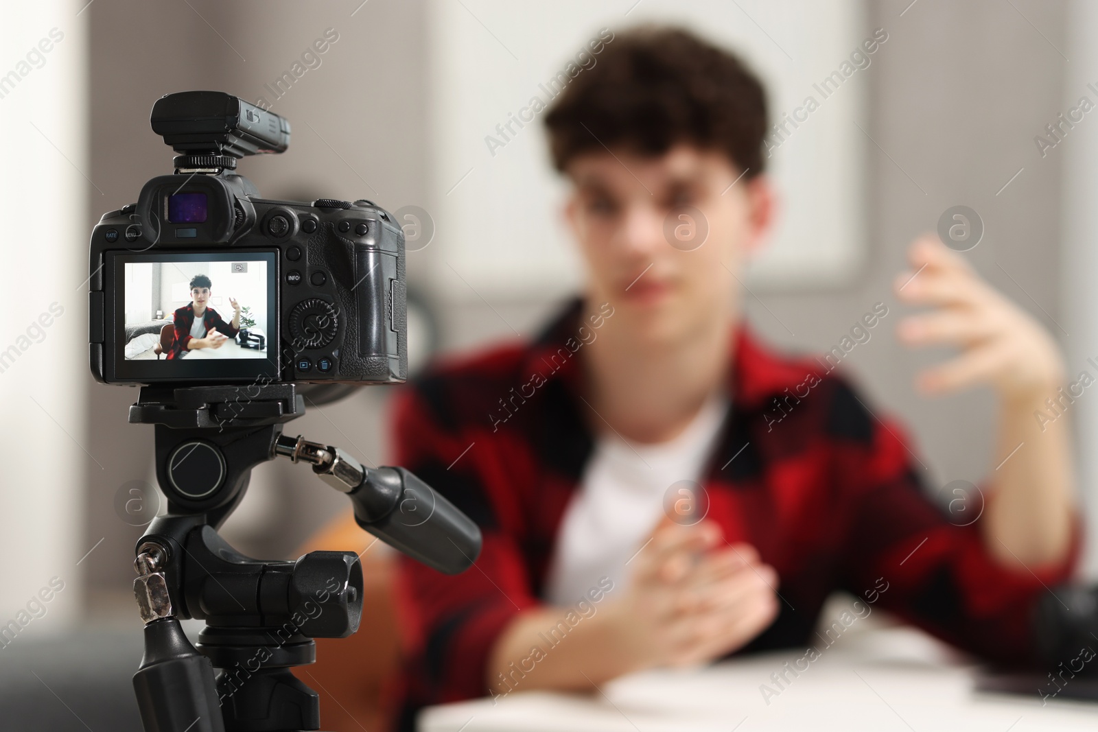 Photo of Teenage blogger explaining something while streaming at home, focus on camera