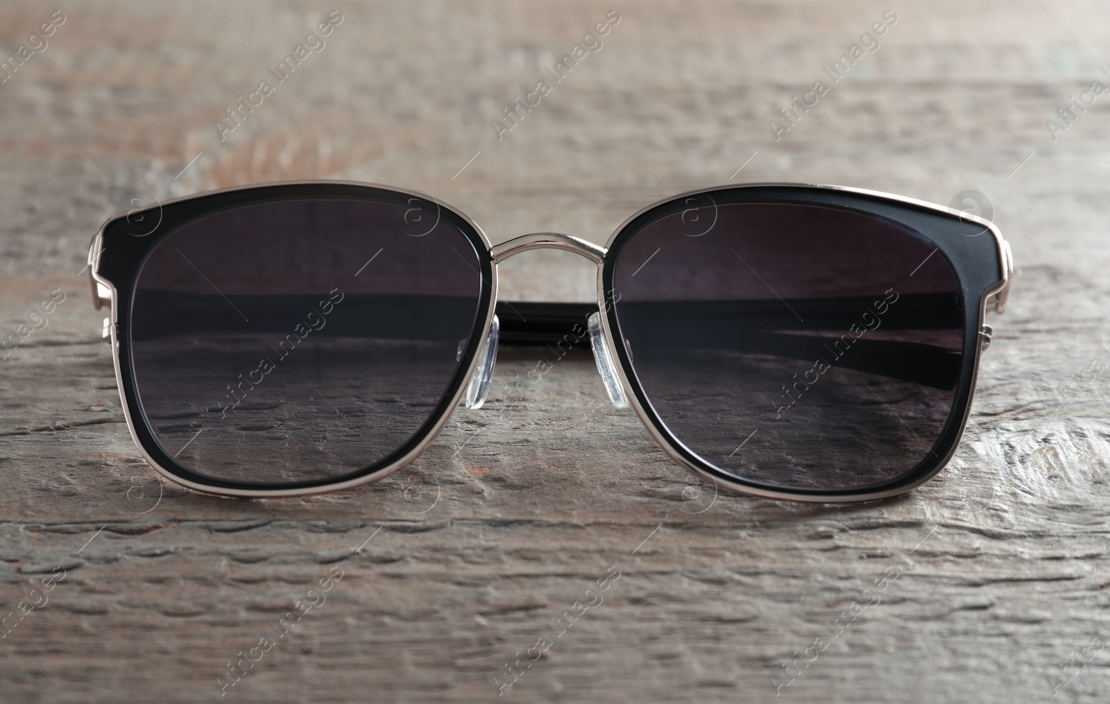 Photo of Stylish sunglasses on wooden background, closeup view
