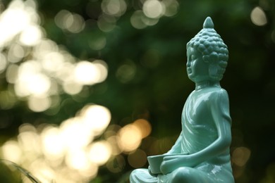 Decorative Buddha statue on blurred background outdoors. Space for text