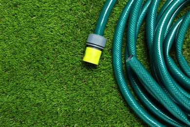 Watering hose on green grass, top view. Space for text