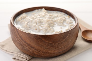 Photo of Tasty boiled oatmeal in bowl on white table, closeup