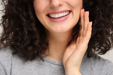 Photo of Young woman using teeth whitening strip, closeup