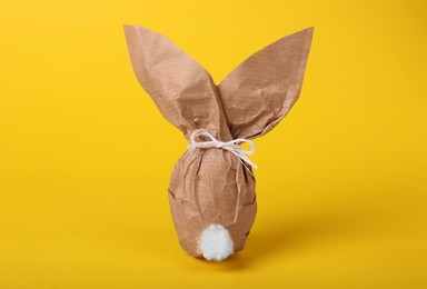 Photo of Easter bunny made of kraft paper and egg on yellow background