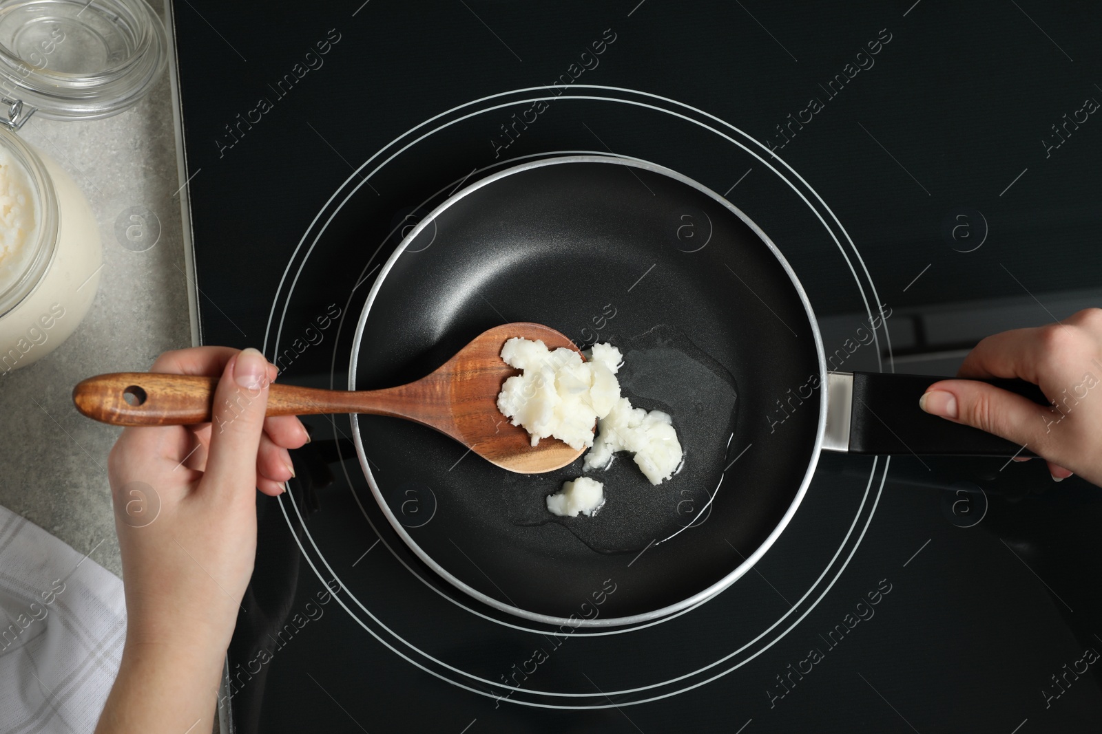 Photo of Woman cooking with coconut oil on induction stove, top view