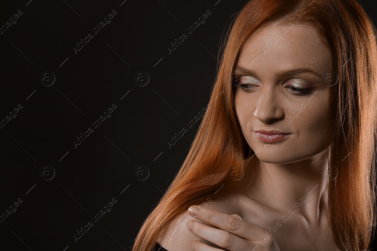 Photo of Portrait of happy young woman with charming smile and gorgeous red hair on dark background, space for text