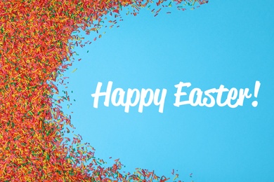 Text Happy Easter and colorful sprinkles on light blue background, flat lay. Confectionery decor