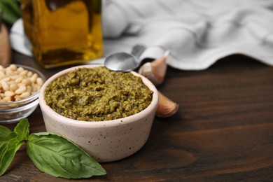 Tasty pesto sauce and ingredients on wooden table, closeup. Space for text