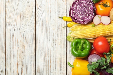 Photo of Flat lay composition with assortment of fresh vegetables on wooden background. Space for text