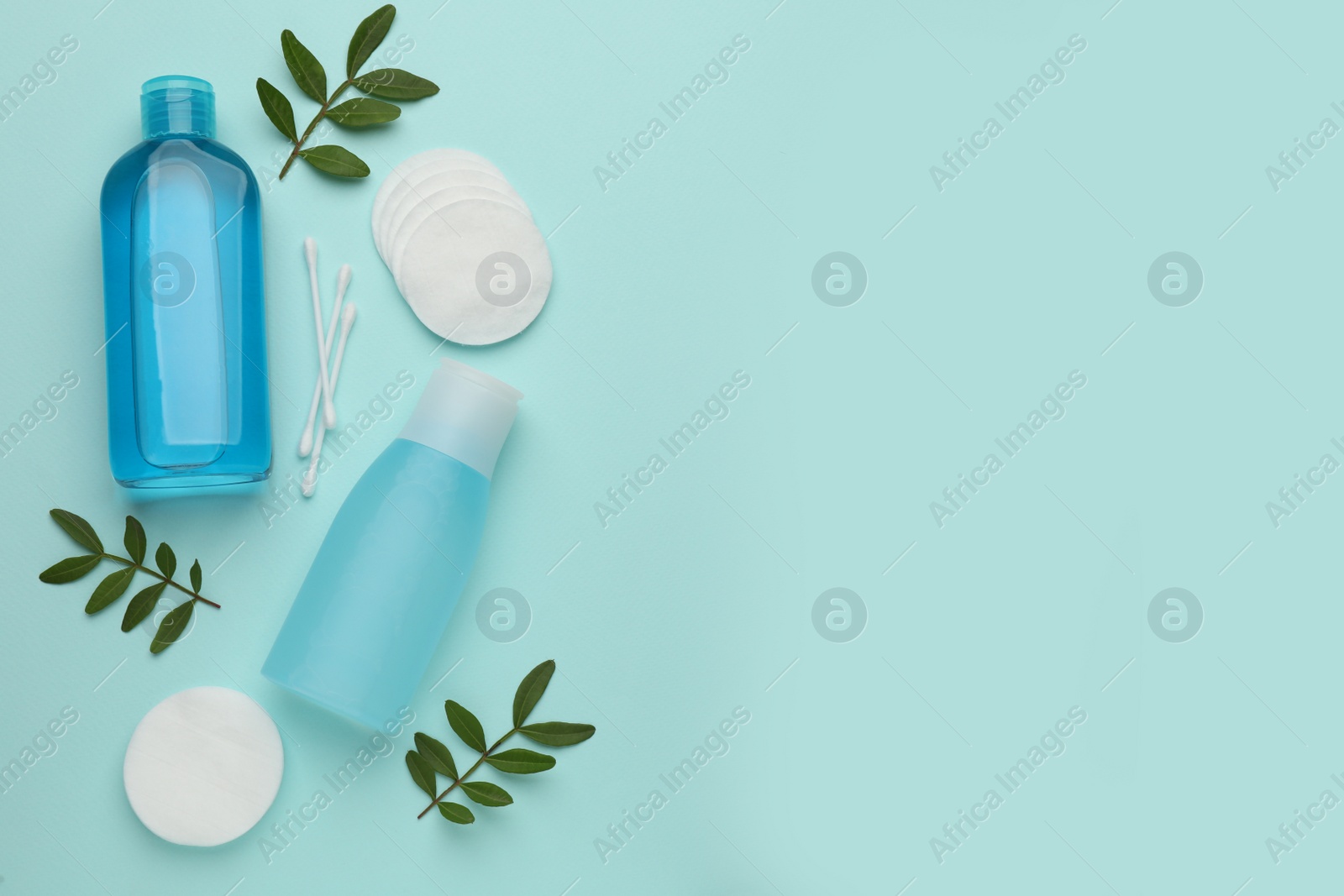 Photo of Cotton pads, swabs, leaves and makeup removal products on light blue background, flat lay. Space for text