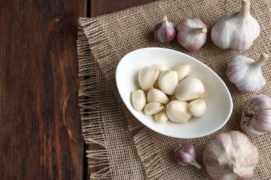 Photo of Fresh garlic bulbs and cloves on wooden table, flat lay. Space for text