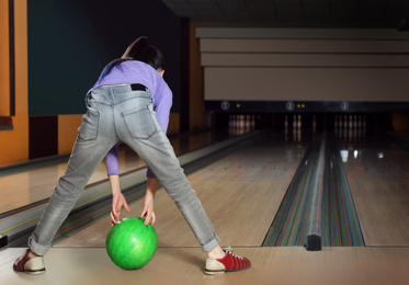 Photo of Girl throwing ball in bowling club, back view