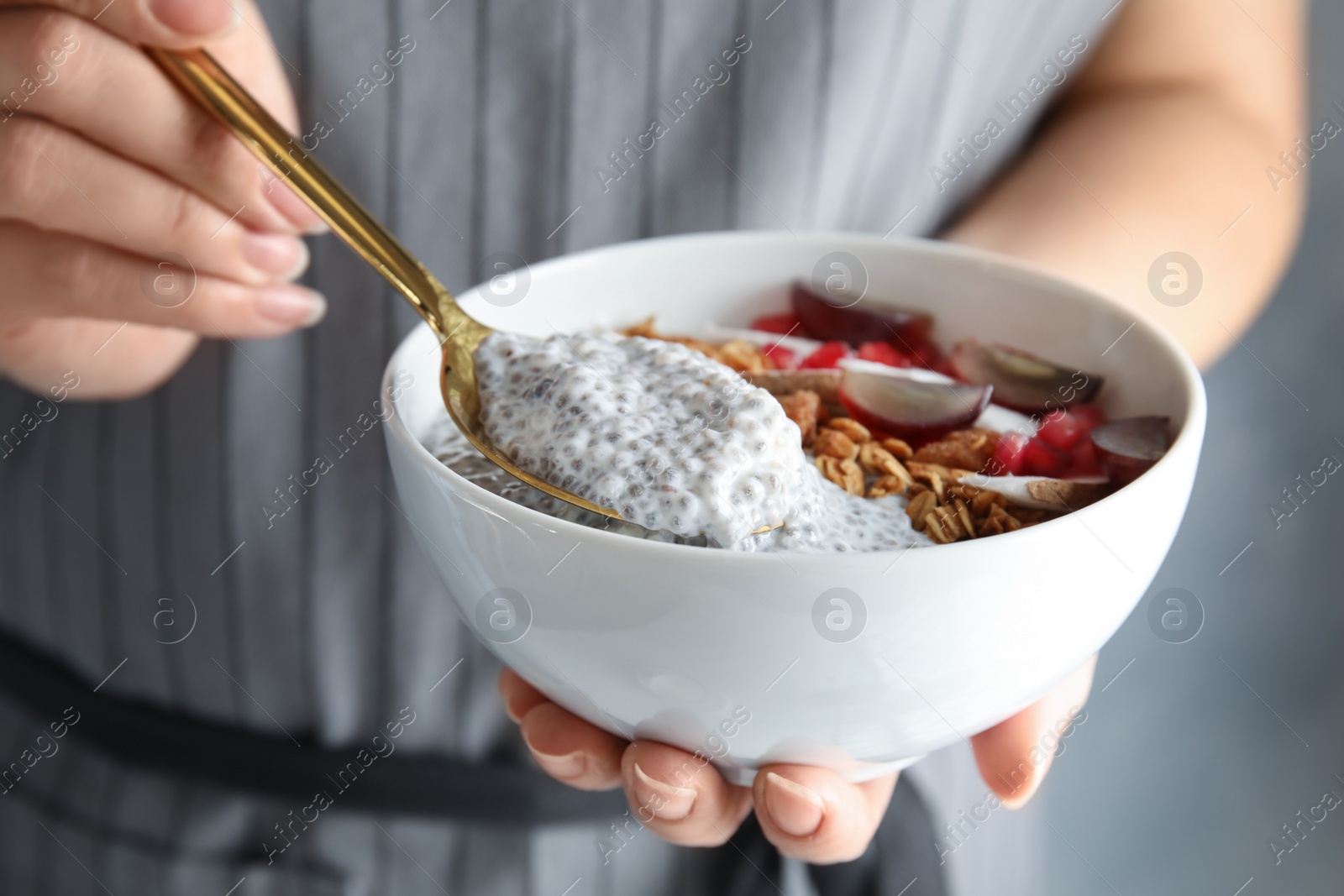 Photo of Young woman eating tasty chia seed pudding, closeup