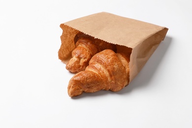 Paper bag with delicious croissants on white background