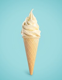 Image of Tasty vanilla ice cream in waffle cone on pastel light blue background. Soft serve