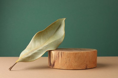 Photo of Presentation for product. Wooden podium and dry leaf on color background. Space for text