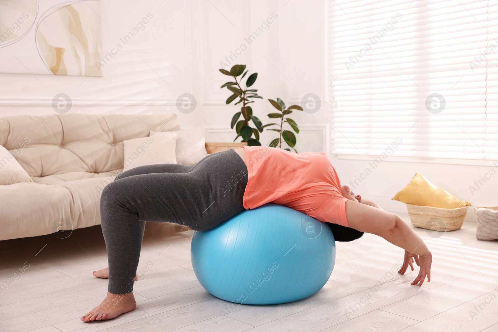 Photo of Overweight mature woman doing exercise with fitness ball at home