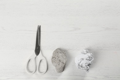 Flat lay composition with rock, paper and scissors on white wooden background