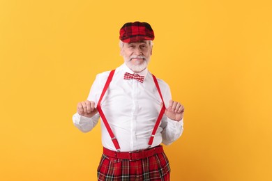 Portrait of grandpa with stylish hat and bowtie on yellow background