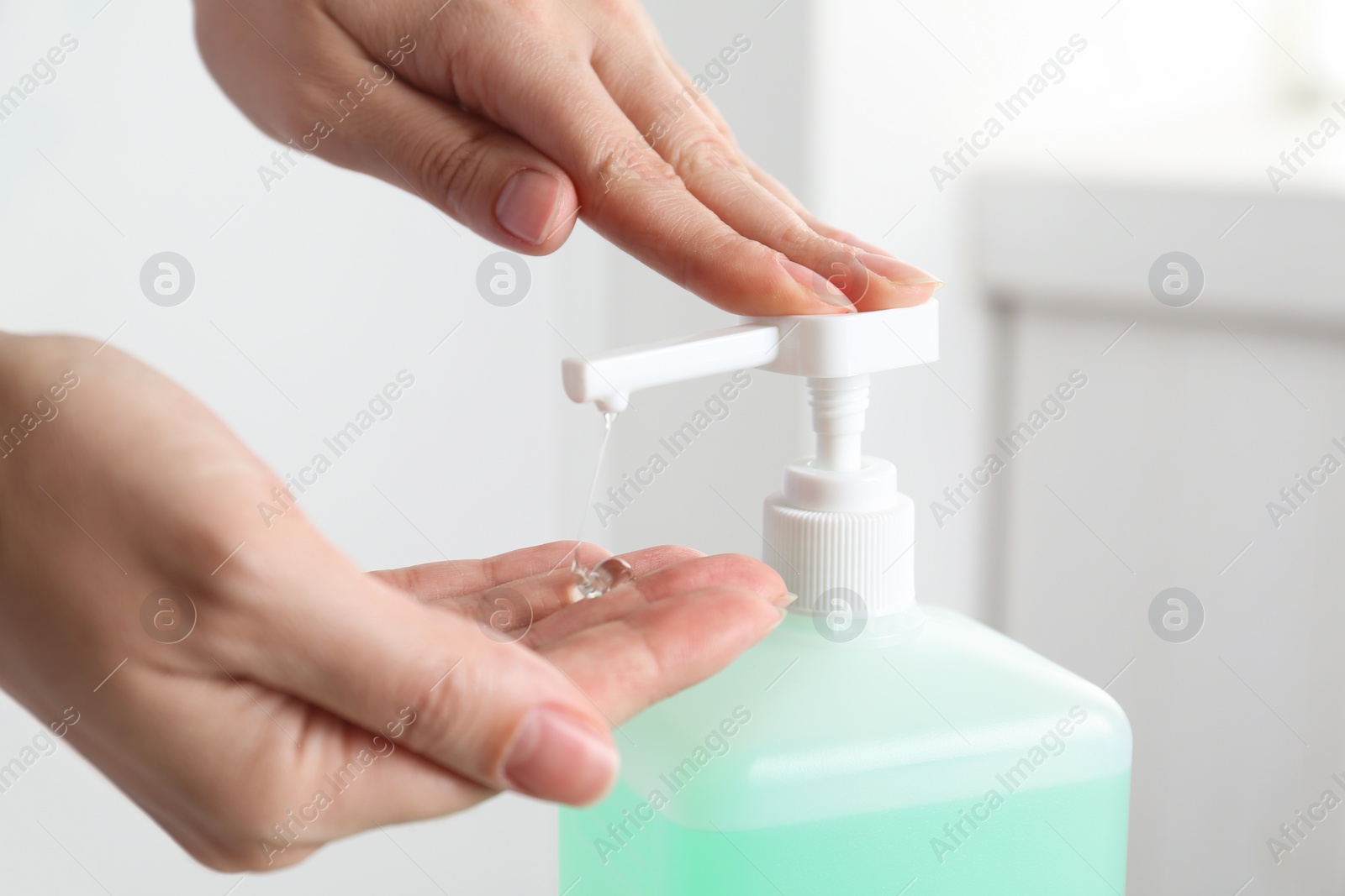 Photo of Woman applying antiseptic gel on hand indoors, closeup