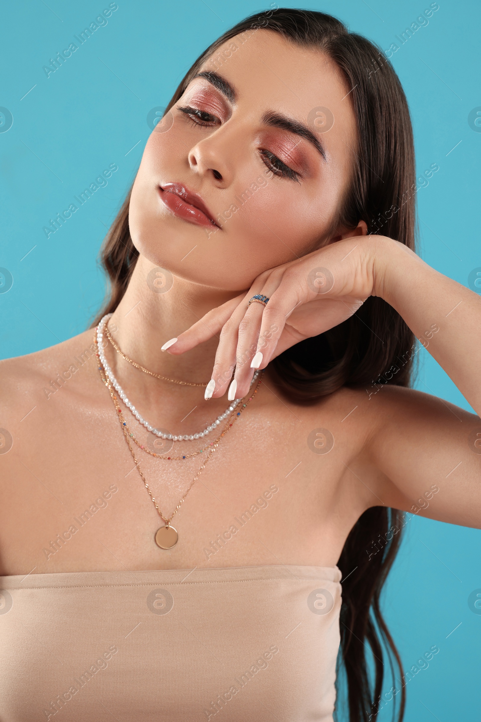 Photo of Beautiful woman with elegant jewelry on light blue background