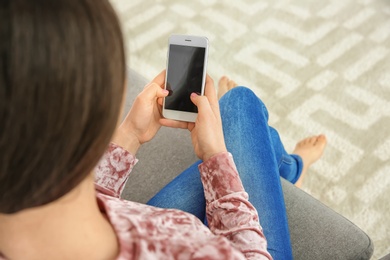 Photo of Young woman using mobile phone at home