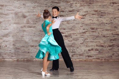 Beautifully dressed couple of kids dancing together in studio