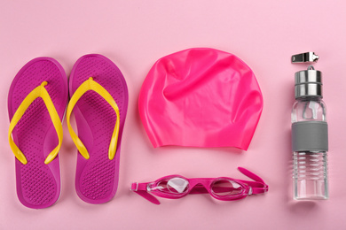 Flat lay composition with swimming accessories on pink background