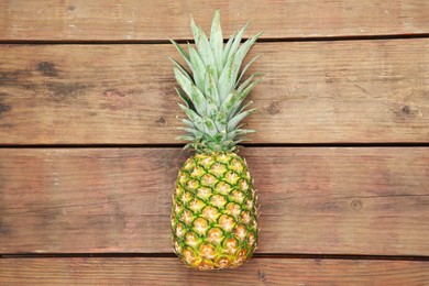 Photo of Delicious ripe pineapple on wooden table, top view