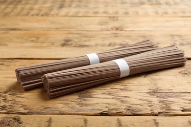 Uncooked buckwheat noodles (soba) on wooden table, closeup