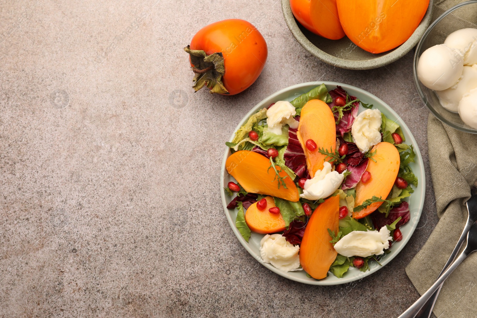 Photo of Delicious persimmon salad with cheese and pomegranate served on grey table, flat lay. Space for text