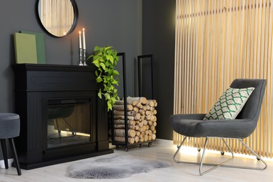 Photo of Stylish room with beautiful fireplace, houseplant and comfortable chair. Interior design