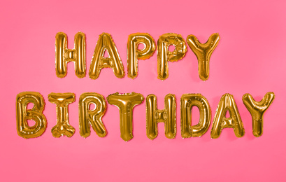 Phrase HAPPY BIRTHDAY made of foil balloon letters on pink background