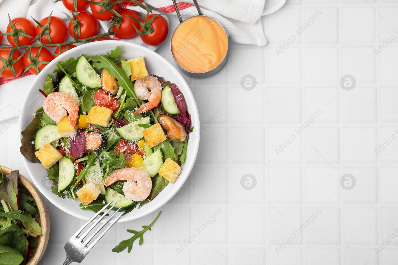 Photo of Delicious salad with croutons, cucumber and shrimp served on white tiled table, flat lay. Space for text