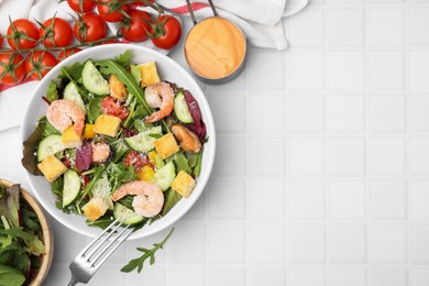 Photo of Delicious salad with croutons, cucumber and shrimp served on white tiled table, flat lay. Space for text