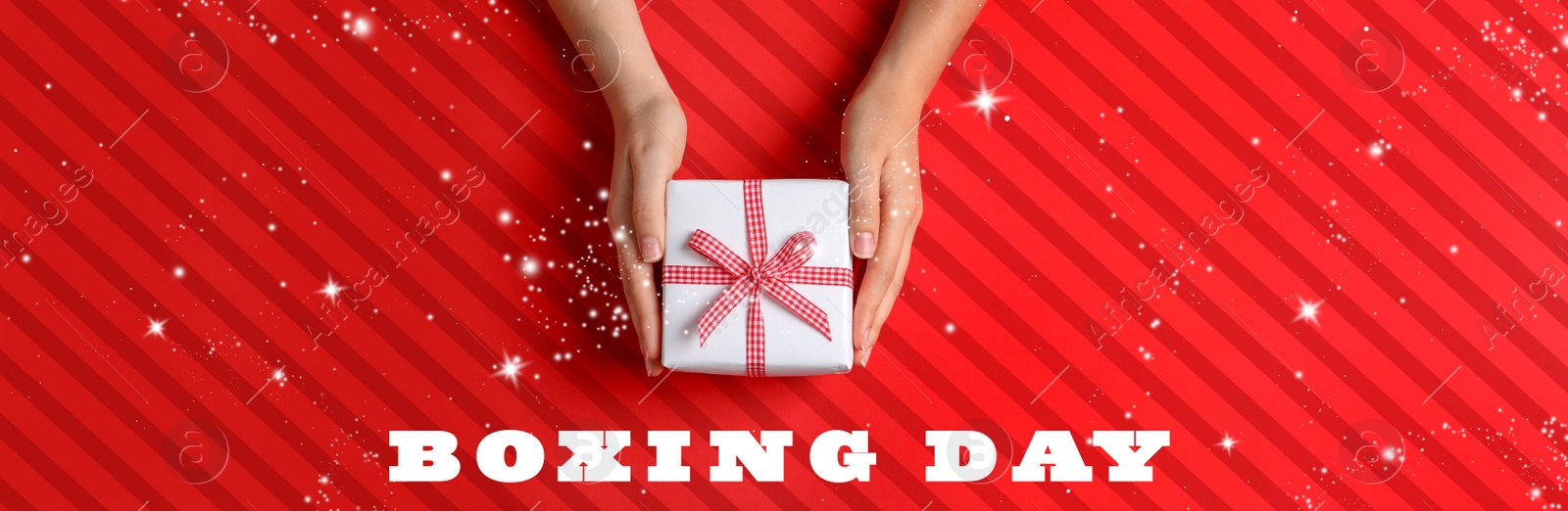 Image of Boxing day banner design. Woman holding gift on red striped background, top view