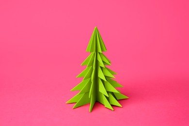 Photo of Origami art. Handmade paper Christmas tree on pink background