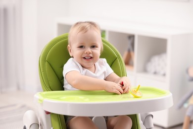 Photo of Children toys. Cute little boy playing with spinning tops in high chair at home