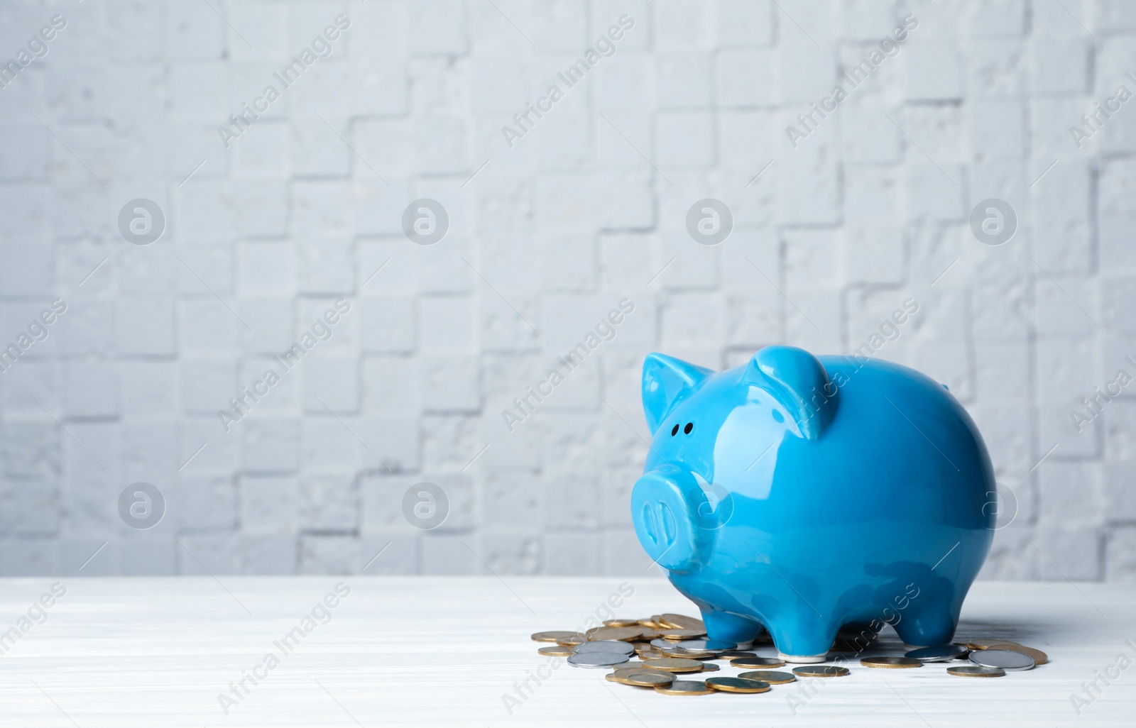 Photo of Piggy bank with coins on table. Space for text