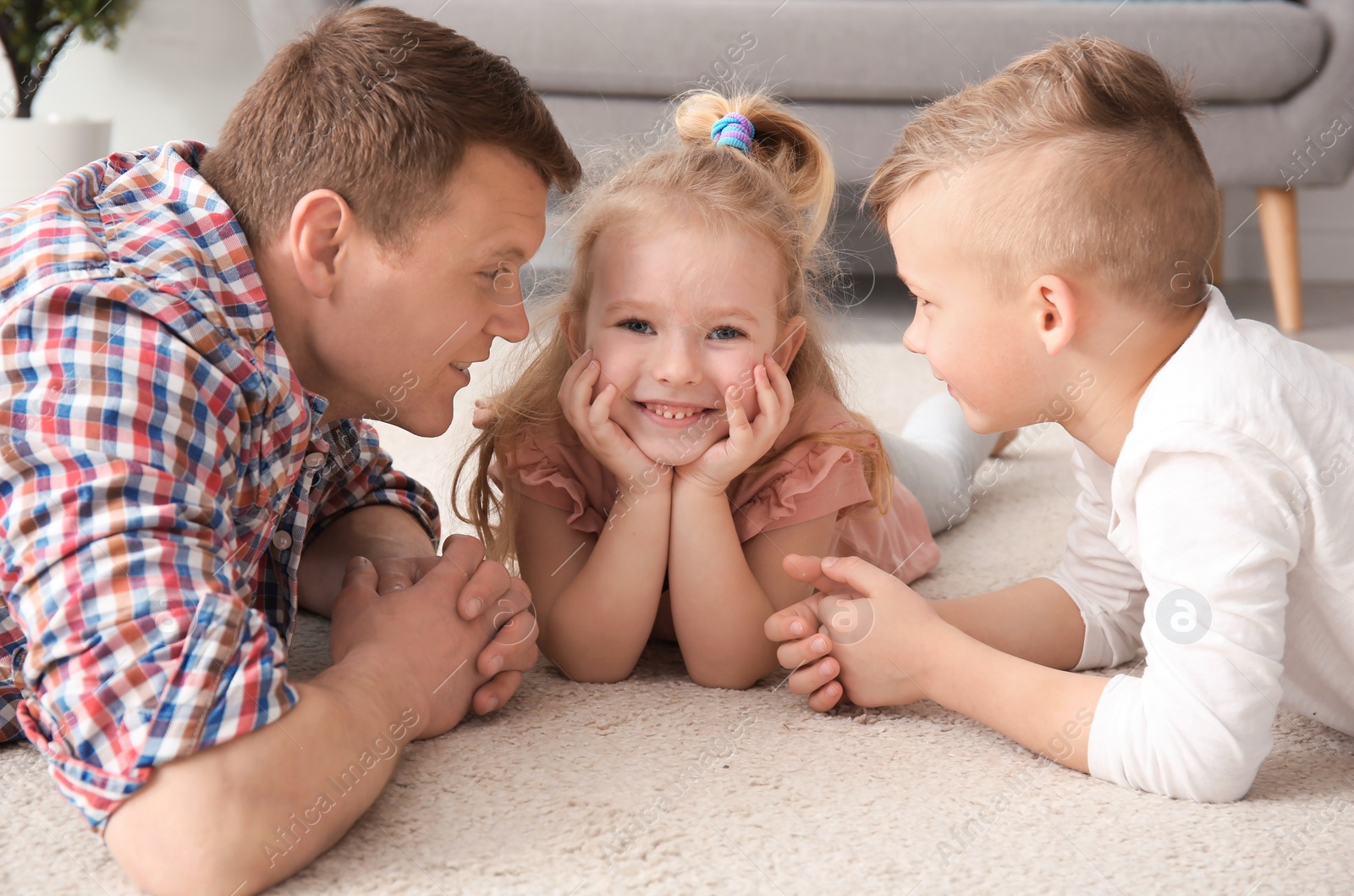 Photo of Cute little children and their father lying on cozy carpet at home