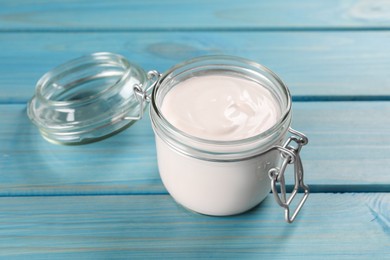 Photo of Jar of tasty organic yogurt on light blue wooden table