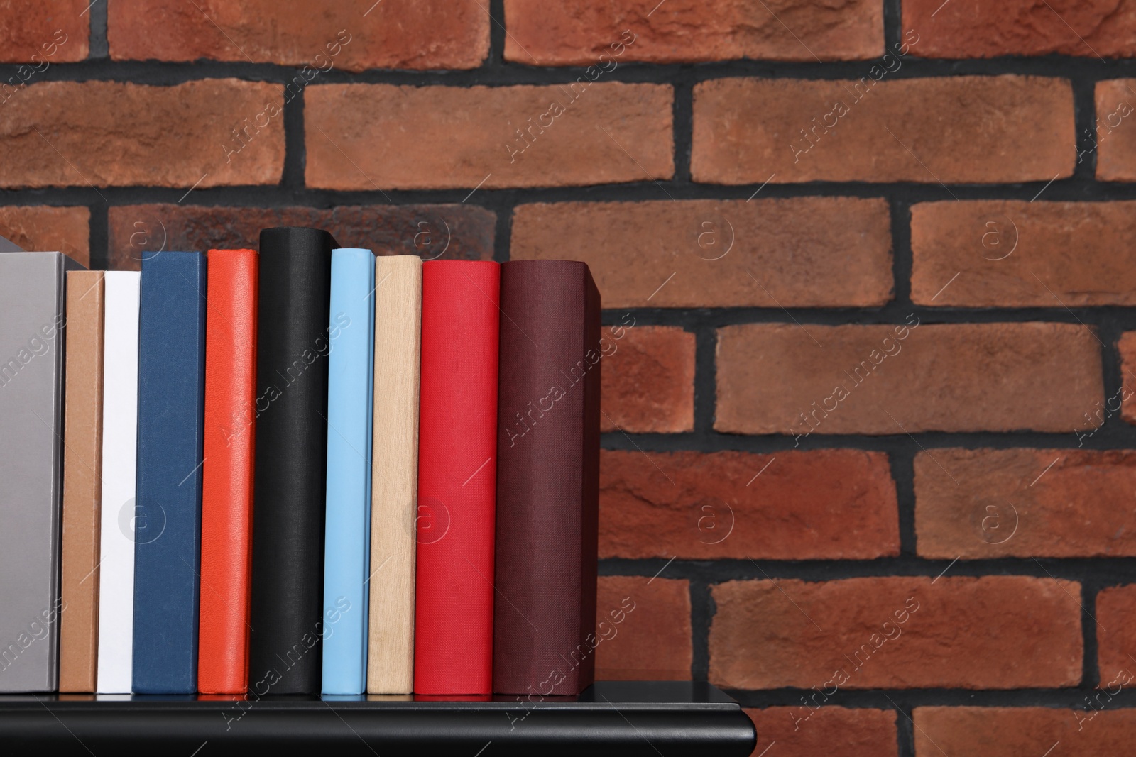 Photo of Many different hardcover books on black wooden table. Space for text