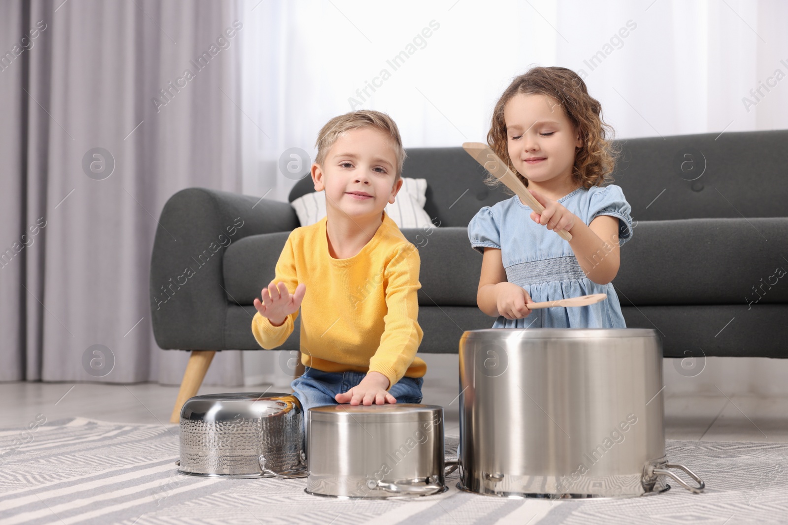 Photo of Little children pretending to play drums on pots at home