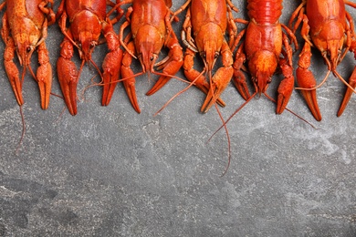 Photo of Delicious boiled crayfishes on grey table, flat lay. Space for text