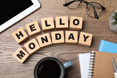 Photo of Cubes with message Hello Monday, office stationery and cup of coffee on wooden desk, flat lay