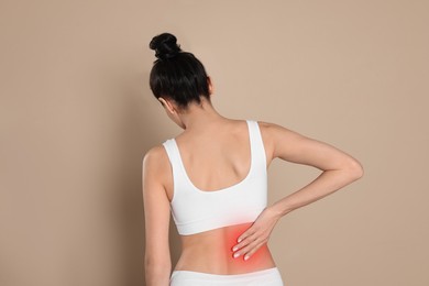 Image of Woman suffering from pain in lower back on beige background